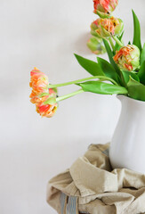Tulips bouquet in white vase on wooden rustic chair