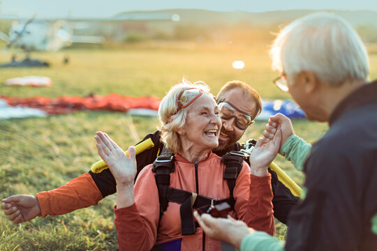 Happy senior woman landing with skydiving instructor