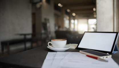 Latte coffee on table in cafe by the window with tablet and smart phone. taking a break during a day with coffee drink in cafe and checking work documents