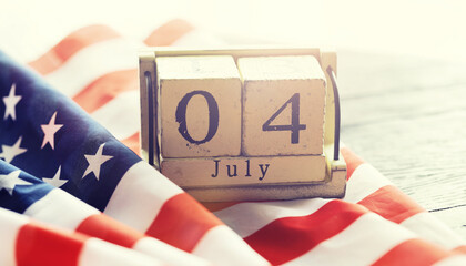 Cube shape calendar for July 04 on wooden table on usa flag background