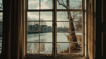  a window that has a view of a body of water and a building in the distance with a tree in the foreground.