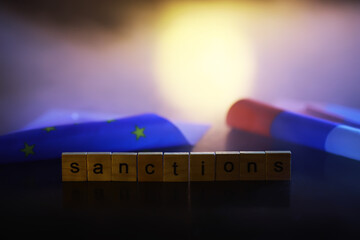 Word Sanctions made of wooden block letters with dramatic lighting and smoke