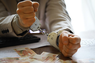 Hands in handcuffs behind, holding five thousand rubles. Concept of corruption