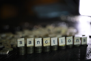 Word Sanctions made of wooden block letters with coins stacks