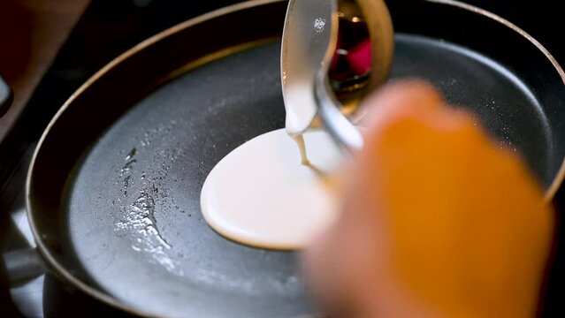 Closeup of making steaming hot crepe layer on a cast iron pan. A thin pancake made with rice flour dough and condensed milk stuffing. Thin batter being spread and cooked for making 'Pithe' and 'dosa'