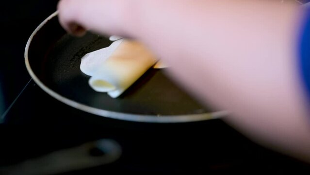 Closeup of making steaming hot crepe layer on a cast iron pan. A thin pancake made with rice flour dough and condensed milk stuffing. Thin batter being spread and cooked for making 'Pithe' and 'dosa'