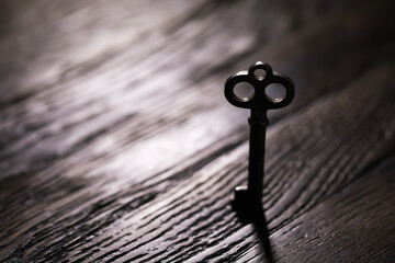 An vintage key on an grungy old desk with a beam of light coming in.