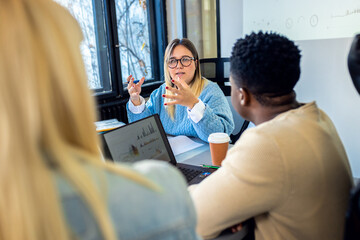 Diverse group of young business people working on new project together in office.