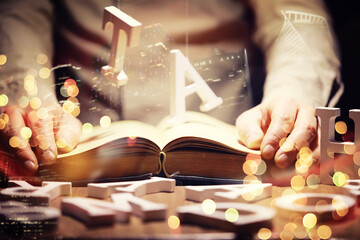 Close up of an unrecognizable man holding a book standing against a evening city panorama. Mock up,...