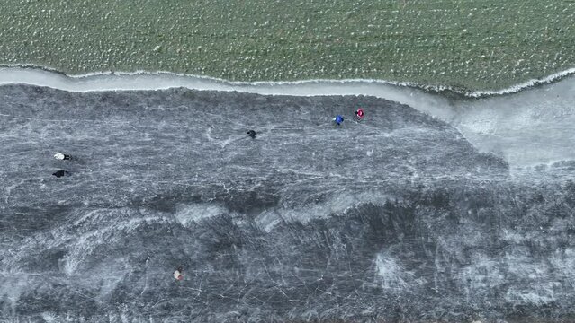 Ice skating on the Drontermeer lake near Elburg in nature seen from above during a cold winter day in The Netherlands.