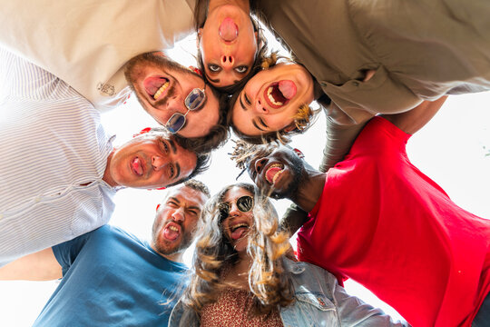 
Multicultural friends heads circle round with funny faces and smile - Happy multiracial students smiling and sticking out tongue at camera looking down - Diverse group of friends lying taking silly 