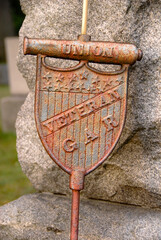 Bronze Union soldier grave marker in cemetery leaning against headstone. Flag and canon design.