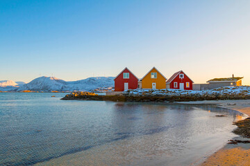 Traditional red and yellow wooden norwegian cabins with ground on the roof. Tromso, Norway