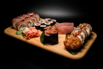 Wooden board isolated on which lies a set of different sushi rolls with tuna