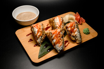 Sushi rolls sandwich tempura covered in brown sauce with wasabi and ginger