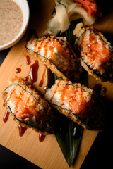Close-up photo of fried salmon tempura sushi roll sandwich covered in sauce