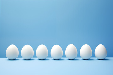 A row of white eggs perfectly aligned against a stark blue background, embodying a minimalist and clean aesthetic.

