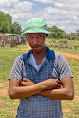 young african man with a green hat in the village in a summer day