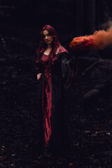a woman in a dark forest with coat and pumpkin