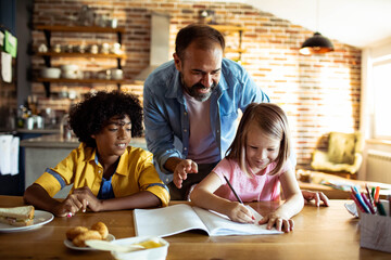 Father helping his diverse children with homework at home - obrazy, fototapety, plakaty