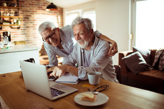 Smiling Senior Couple Using Laptop Together At Home