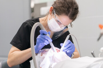 A female dentist performs an oral hygiene and dental cleaning procedure using an air abrasion device. Aesthetic dentistry for the prevention of caries and periodontal disease.