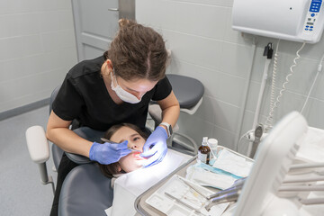 A female pediatric dentist provides emergency dental care to a child. Periodic scheduled visits to...