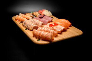 Side view of a set of nigiri with different types of fish, cold and fried, covered with sauce