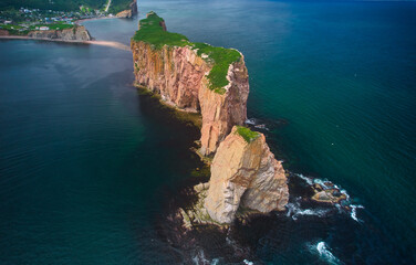 The beautiful colors, natural arch and shape of famous Perce Rock on the Gaspe Peninsula in Quebec Canada with the exposed sandbar at lowtide for access to the rock from an aerial drone image