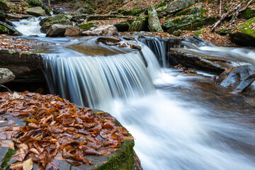 Cascade of waterfalls in a mountain gorge, fast flowing water, long exposure