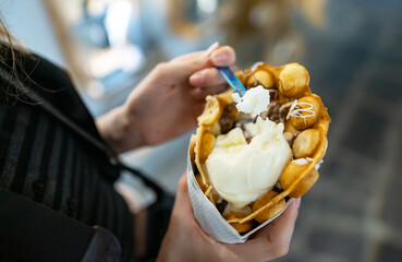 Girl holding waffle with ice cream. Street food.