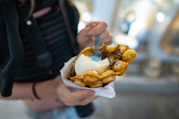 Girl holding waffle with ice cream. Street food.