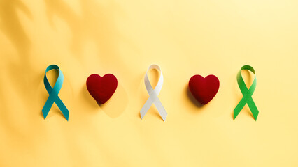 Ribbon and heart on yellow background for cancer awareness day