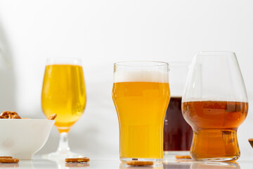 A several glasses with light beer  ale cider on white table
