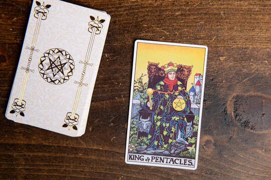 London, UK: 4 January, 2024: Minor Arcana - King of Pentacles of Tarot Card of Rider Waite deck on wooden background