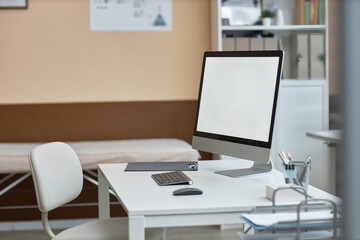 Side view of working computer monitor with blank screen on white office table in private clinic