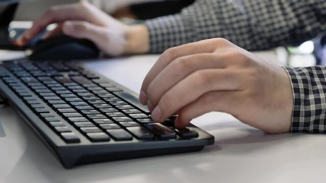 A man is typing on a computer, his fingers are typing on the keyboard. Office work.