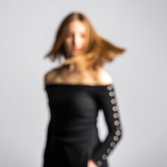 Abstract beauty and fashion concept. Blurred and defocused woman silhouette portrait in movement. Woman with black outfit. Image contains noise, grain and motion blur