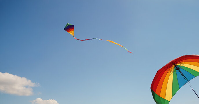 A vibrant image of a kite soaring in the clear sky, painted in a spectrum of colors including red, yellow, green, and blue.