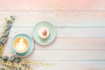 Kaffee und Kuchen auf einem Holztisch angerichtet in Pastellfarben 