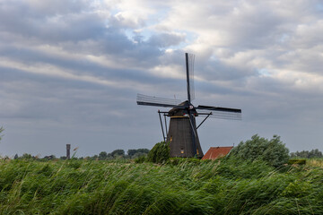 Beautiful wooden windmills at sunset in the Dutch village of Kinderdijk. Windmills run on the wind. The beautiful Dutch canals are filled with water. Beautiful sunset. - 712663239