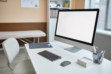 Close up shot of big blank screen computer monitor and office supplies on desk in medical examination room