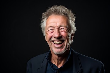 Portrait of a happy senior man laughing on a black background.