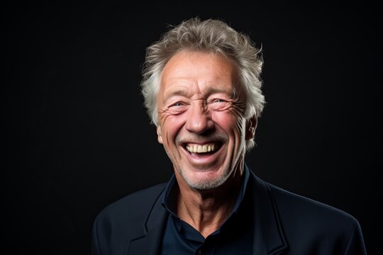 Portrait of a happy senior man laughing on a black background.