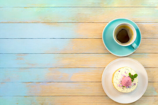 Kaffee und Kuchen auf einem Holztisch angerichtet in Pastellfarben 
