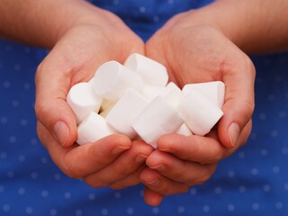 A pile of white marshmallows in woman palms. Close-up.