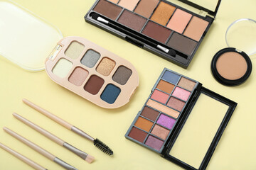 Eyeshadows with brushes on yellow background