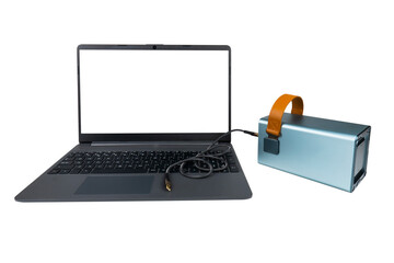 A laptop with a blank transparent screen next to a large power bank (charging station) with a USB...