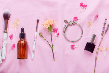 Aesthetic female make up set. Dropper bottle, brushes, jewelry and lavender flat lay