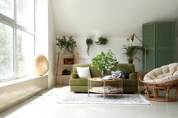 Interior of light living room with green sofa and blooming jasmine flowers on coffee table